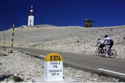 two people riding bikes on a road with a sign at La Bastide des Bourguets Adults Only, Mont Ventoux in Sault-de-Vaucluse