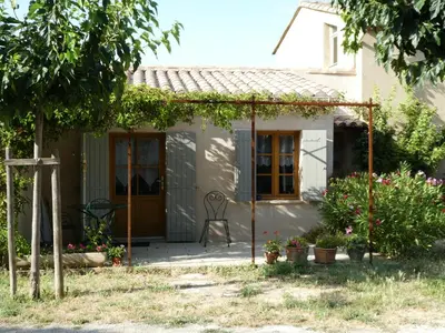 a small white house with a chair on a patio at Les Biguières in Maubec