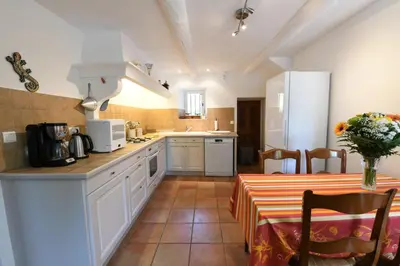 a kitchen with white cabinets and a table with a table cloth at Mas du PERUSSIER in Cucuron