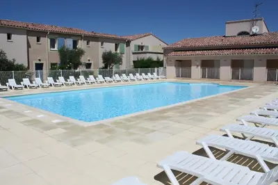 a swimming pool with white lounge chairs and a resort at Charming rental with shared-pool in the Alpilles. in Mouriès