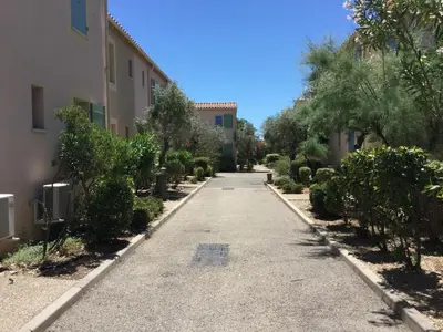 an empty street between two buildings with trees at Charming rental with shared-pool in the Alpilles. in Mouriès