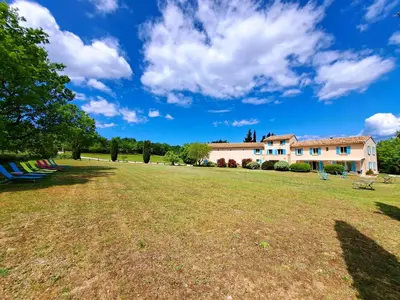 a large grass field with a house in the background at Cante Grillet - 295 Chemin des Contards - 84480 Lacoste in Lacoste