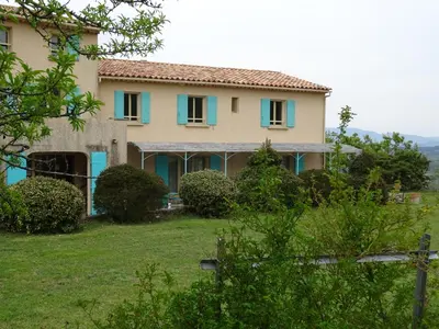 a house with blue shutters on a green yard at Cante Grillet - 295 Chemin des Contards - 84480 Lacoste in Lacoste