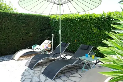 a patio with two chairs and a table with an umbrella at Very pleasant vacation rental with heated pool in the Luberon in Gargas