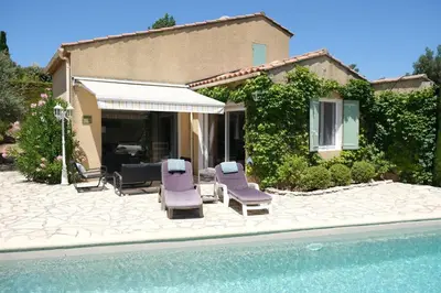 a house with a patio with chairs and a pool at Very pleasant vacation rental with heated pool in the Luberon in Gargas