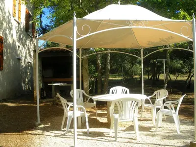 a white table and chairs under an umbrella at Spacious villa on two levels in Cabrières-dʼAvignon