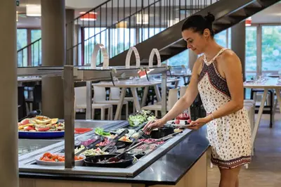 a woman preparing food at a buffet in a restaurant at Belambra Clubs L'Isle Sur La Sorgue - Domaine De Mousquety in LʼIsle-sur-la-Sorgue