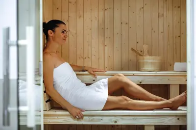 a woman is sitting in a sauna at Belambra Clubs L'Isle Sur La Sorgue - Domaine De Mousquety in LʼIsle-sur-la-Sorgue