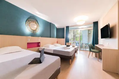 a hotel room with three beds and a laptop on a desk at Belambra Clubs L'Isle Sur La Sorgue - Domaine De Mousquety in LʼIsle-sur-la-Sorgue