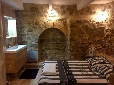 a bedroom with a stone wall with a bed and a sink at Le petit trésor du Luberon in Ménerbes