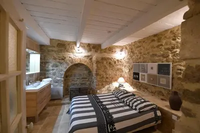 a bedroom with a bed and a stone wall at Le petit trésor du Luberon in Ménerbes