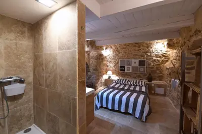 a bedroom with a bed in a room with stone walls at Le petit trésor du Luberon in Ménerbes