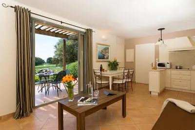 a kitchen and a living room with a table and a kitchen and a dining area at Madame Vacances Domaine du Provence Country Club Service Premium in Saumane-de-Vaucluse