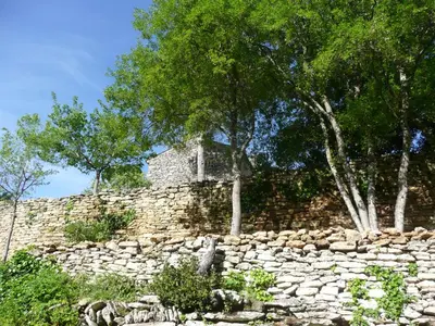 an old stone wall with trees behind it at Belle De Jour -A Provencal gem Private heated pool in Gordes