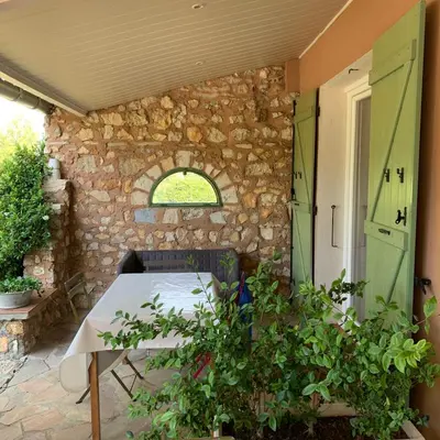 a patio with a table and a stone wall at Chambre d'hôtes Le Cèdre in Apt