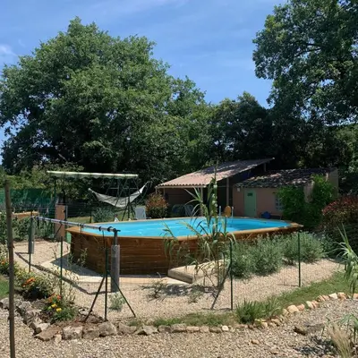 a swimming pool in a garden with a house at Chambre d'hôtes Le Cèdre in Apt