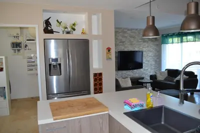 a kitchen with a stainless steel refrigerator and a living room at La cubaine in Puget