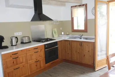 a kitchen with wooden cabinets and a stove top oven at Maison de charme à Mérindol + Jardin in Mérindol