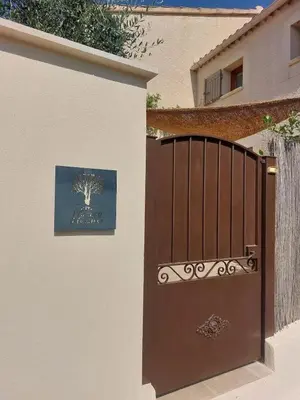 a gate with a picture of a tree on the side of a building at Maison de charme à Mérindol + Jardin in Mérindol