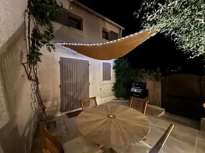 a patio with a table and chairs and an umbrella at Maison de charme à Mérindol + Jardin in Mérindol