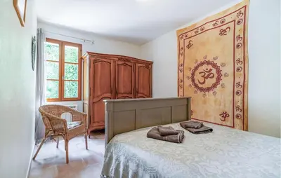 a bedroom with a bed and a chair and a cabinet at Cozy Home In Pernes Les Fontaines in Pernes-les-Fontaines