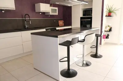 a kitchen with a white counter and stools at very pretty contemporary villa with pool located in Aureille in the alpilles, close to the center on foot. sleeps 4. in Aureille
