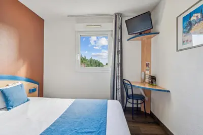 a room with a bed and a desk and a window at Hôtel AKENA Chateaurenard - Parc des Expositions Avignon in Châteaurenard