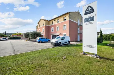 a sign in the grass in front of a building at Hôtel AKENA Chateaurenard - Parc des Expositions Avignon in Châteaurenard
