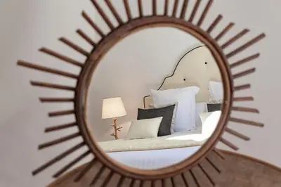 a mirror reflecting a bedroom with a bed with white pillows at Maison Du Collectionneur in Aix-en-Provence