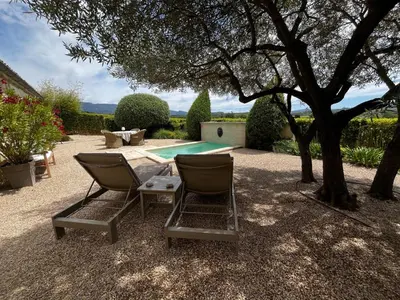 two chairs sitting under a tree next to a pool at Le Mazet d'Emilia avec jardin et piscine privés in Cucuron