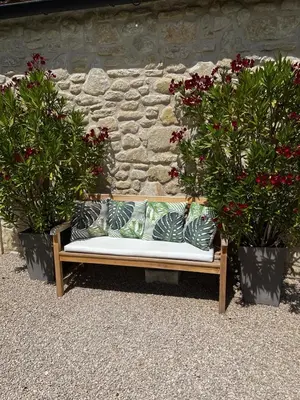 a bench sitting in front of a stone wall with two potted plants at Le Mazet d'Emilia avec jardin et piscine privés in Cucuron