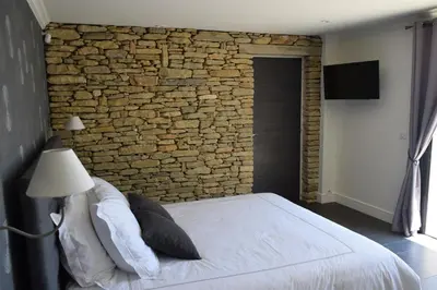 a bedroom with a stone wall and a bed at Le Mazet d'Emilia avec jardin et piscine privés in Cucuron