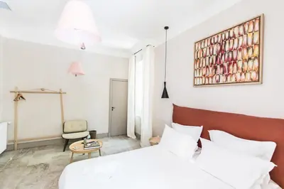 a white bedroom with a bed and a chair at Bastide de Ganay - Saint Jérôme in Aix-en-Provence