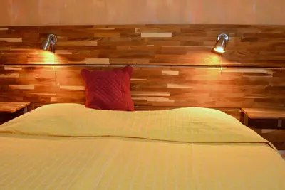 a bed with a wooden headboard with two lights on it at La Tuilière en Luberon in Cadenet
