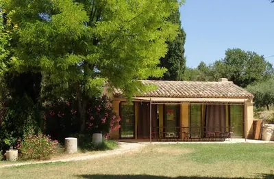 a small house with chairs and a tree at La Tuilière en Luberon in Cadenet