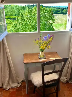 a table with a vase of flowers and a window at 40 Rue du Ventoux in Bédoin