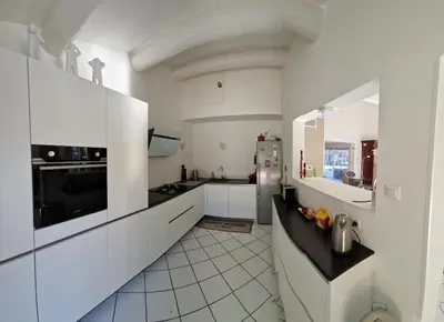 a kitchen with white cabinets and a black counter top at Détente champêtre in Lambesc