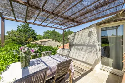 a patio with a table and a pergola at Mas Oréa Sous la glycine in Gordes