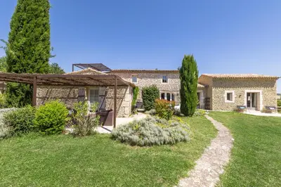a stone house with a garden in front of it at Mas Oréa Sous la glycine in Gordes