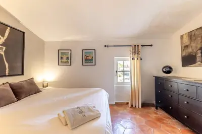 a bedroom with a bed and a dresser and a window at Mas Oréa Sous la glycine in Gordes