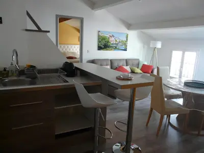 a kitchen with a sink and a table and a couch at Miel de Lavande in LʼIsle-sur-la-Sorgue