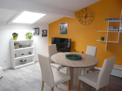 a dining room with a wooden table and white chairs at Miel de Lavande in LʼIsle-sur-la-Sorgue