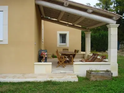 a patio with a wooden table under a pergola at Villa confortable avec piscine privée à Saint-Saturnin-lès-Apt in Croagnes
