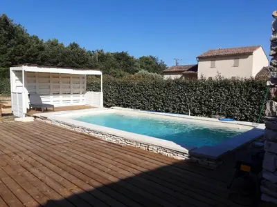 a swimming pool on a wooden deck next to a house at Villa confortable avec piscine privée à Saint-Saturnin-lès-Apt in Croagnes