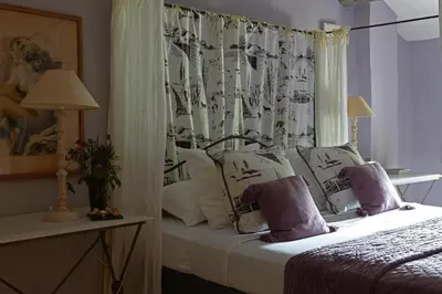 a bedroom with a bed with white pillows and a curtain at Villa Grenache, La Bastide de Marie, Villa avec services in Ménerbes