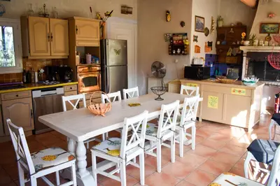 a kitchen with a table and white chairs and a refrigerator at Bastide Les Basses Royères in Robion en Luberon
