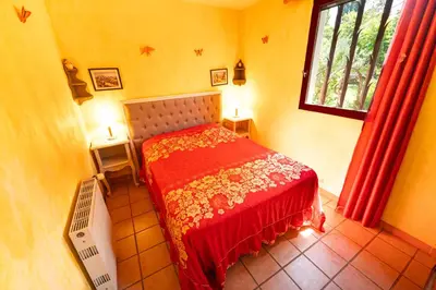 a bedroom with a bed with a redspread and a window at Bastide Les Basses Royères in Robion en Luberon