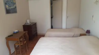 a room with two beds and a table and a cabinet at Chambres d'hôtes de la gardy in Eyragues