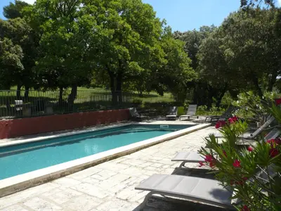 a swimming pool with chaises and chairs in a yard at Chambres d'hôtes de la gardy in Eyragues