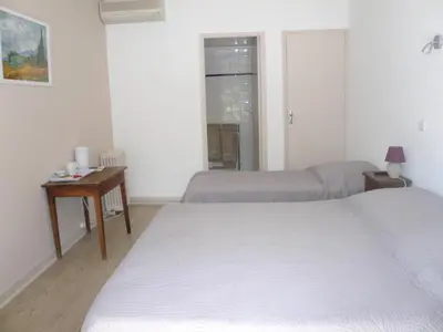 a bedroom with two beds and a table and a window at Chambres d'hôtes de la gardy in Eyragues